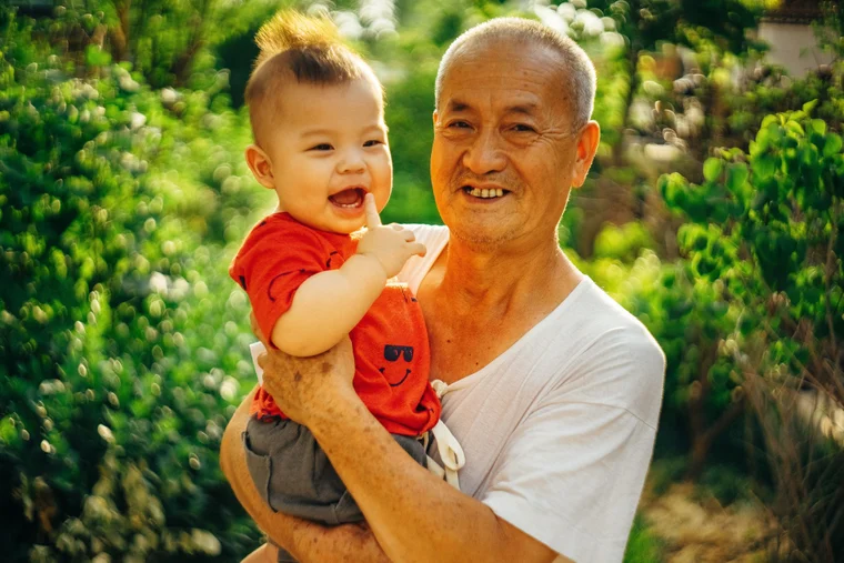 elderly asian man holding an asian baby