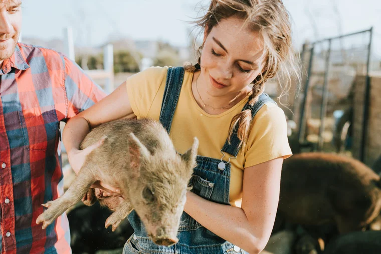 farmer girl holding a young pig