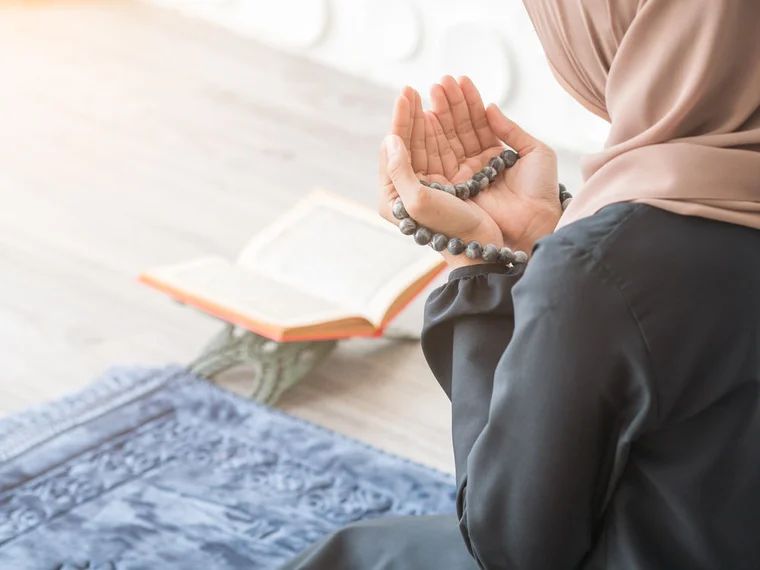 islamic woman praying in front of book