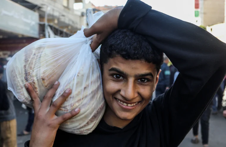 young man carrying bag of bread