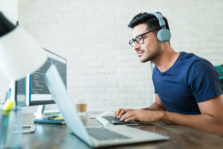 man with glasses looking and typing on computer